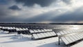 Solar panel array covered in snow under a dramatic cloudy winter sky Royalty Free Stock Photo