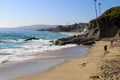 Vast blue ocean water crashing into the rocks along the beach with homes along the coastline with lush green palm trees Royalty Free Stock Photo