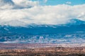 A vast colorful desert landscape under snow-capped mountains and winter storm clouds Royalty Free Stock Photo