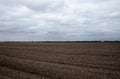 A vast field with ploughed soil under a cloudy sky