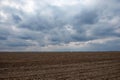 A vast field with ploughed soil under a cloudy sky