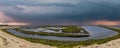 Vast miles of lush green marsh surrounded by deep blue ocean water with powerful clouds at sunset at Bolsa Chica