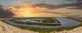 Vast miles of lush green marsh surrounded by deep blue ocean water with powerful clouds at sunset at Bolsa Chica