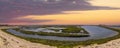 Vast miles of lush green marsh surrounded by deep blue ocean water with powerful clouds at sunset at Bolsa Chica