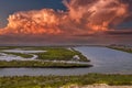 Vast miles of lush green marsh surrounded by deep blue ocean water with powerful clouds at sunset at Bolsa Chica Reserve