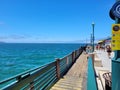Vast miles of rippling blue ocean water with mountain ranges covered in homes at Redondo Beach Pier with people walking