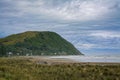 Vast ocean beach surrounded by rugged mountains. Heavy clouds and thick mist over riptide. Makorori beach, Gisborne