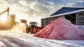 A vast pile of pink sand stands prominently in front of a towering factory where potash fertilizers are processed and stored