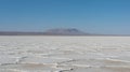 Vast salt flat stretches towards a distant mountain under a clear sky Royalty Free Stock Photo