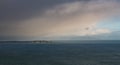 Vast seascape with island illuminated through a break in storm clouds