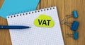 VAT - word written in a notebook on a wooden background with a pen and clamps Royalty Free Stock Photo