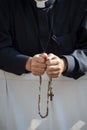 A priest pray with his wood rosary.