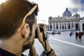 Vatican City, Roma, Italy. Young man taking photo of St Peter`s square with the famous Basilica in the background Royalty Free Stock Photo