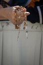 An elderly woman holds a wood holy rosary in her hand