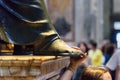 Person touching the foot of Saint Peter statue. Interior of Saint Peter`s Basilica in Vatican