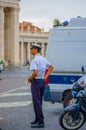 VATICAN, ITALY - JUNE 13, 2015: Elegant italian police preparing himself, next to a car and moto. Blue uniform