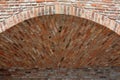 Vault in a wall of burnt bricks. The bricks are arched at an angle to each other. such a niche serves as a place to sit in the gar Royalty Free Stock Photo