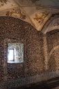 Vaulted ceiling with allegorical religious paintings and the wall decorated with human bones and skulls with daylight entering Royalty Free Stock Photo