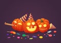 Three happy pumpkins in party hats with party blowout and sweets. Royalty Free Stock Photo