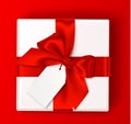 Realistic white gift box with reb bow and empty sale tag on red background. Holiday decorations. Vector present