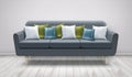 Vector illustration of gray sofa with cushions on wooden floor and white wall. White, blue, and green pillows on settee