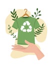 Vector illustration of hand holding green recycling t-shirt, clothes hanger, recycle symbol isolated on white background - Royalty Free Stock Photo