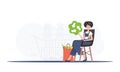 The girl is sitting next to a package with healthy food and holding an EKO icon. The concept of ecology, zero waste and Royalty Free Stock Photo