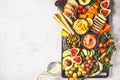 Vegan appetizer platter. Hummus, tofu, vegetables, fruits and bread on black tray, copy space