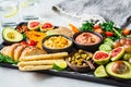 Vegan appetizer platter. Hummus, tofu, vegetables, fruits and bread on black tray, copy space