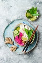 Vegan asian udon noodles soup bowl with ginger and mushrooms broth, tofu, snap peas, zucchini, watermelon radish and lime