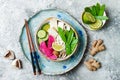 Vegan asian udon noodles soup bowl with ginger and mushrooms broth, tofu, snap peas, zucchini, watermelon radish and lime