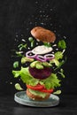 Vegan beetroot burger with flying ingredients on black background. Food levitation concept. Vegetarian food