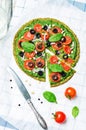 Vegan broccoli zucchini pizza crust with spinach pesto, tomatoes, onion and olives