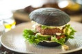 Vegan burger. Black bun, tofu-avocado salad, mayonnaise, cucumber, tomato, fresh salad. Delicious healthy hamburger food