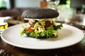 Vegan burger. Black bun, tofu-avocado salad, mayonnaise, cucumber, tomato, fresh salad. Delicious healthy hamburger food