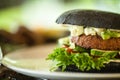 Vegan burger. Black bun, tofu-avocado salad, mayonnaise, cucumber, tomato, fresh salad. Delicious healthy hamburger food