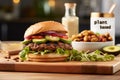 Vegan burger with plant based meat, avocado, tomato, red onion, vegan mayonnaise and green salad leaves on a fresh bun with flax Royalty Free Stock Photo