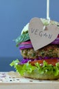 Vegan burger with quinoa and green peas vegetable patty, lettuce, onion, tomato, red cabbage, and spinach on dark background Royalty Free Stock Photo