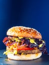 Vegan burger on a slate plate. blue background. Vertical.