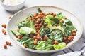 Vegan caesar salad with fried spicy chickpeas in a gray bowl