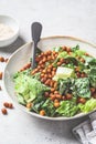 Vegan caesar salad with fried spicy chickpeas in a gray bowl