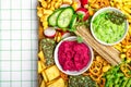 Vegan charcuterie board with beetroot and green pea hummus, various crackers, fresh vegetables. Closeup view