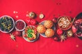 Vegan Christmas appetizers, olive, orange, fruits, vegetable salads, candles, tangerine, pomegranate, star glitter sparkles on red Royalty Free Stock Photo