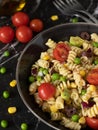 Vegan colorful Italian pasta salad in a bowl with cherry tomatoes, green peas, corn, avocado, olives, olive oil, and spices Royalty Free Stock Photo