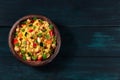 Vegan couscous with vegetables, almonds, chickpeas and herbs, shot from above on a dark wooden background