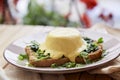 Vegan eggs benedict dish with plant-based sauce, whole grain bread, smoked tofu, young onion, greens, pea sprouts Royalty Free Stock Photo