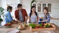 Vegan family. Mother, father and two little excited kids cooking together in the kitchen at home. They preparing a salad Royalty Free Stock Photo