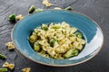 Vegan Farfalle pasta in a spinach sauce with broccoli, brussels sprouts, green beans in plate on dark stone background. Top view