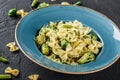 Vegan Farfalle pasta in a spinach sauce with broccoli, brussels sprouts, green beans in plate on dark stone background