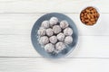 Vegan food energy balls with prunes, almond and coconut. White wooden background. Minimalism concept